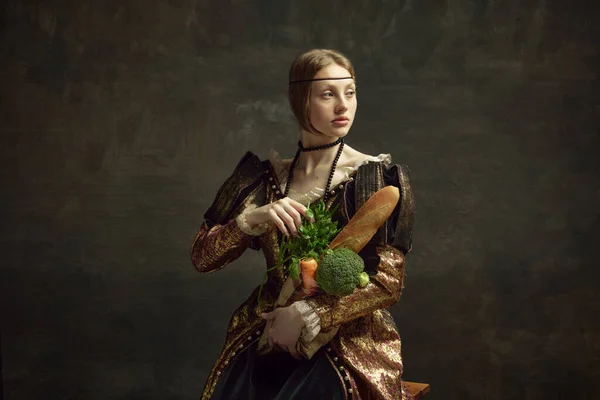 年轻美丽的女孩的画像 古色古香的公主 雅致的服装与面包和蔬菜的深绿色背景 历史的概念 复兴的艺术 时代的比较 食品采购 — 图库照片