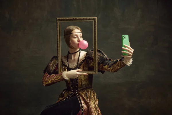かなり若い女の子の肖像画 バブルガムでプリンセス 写真フレームを保持し 暗い緑の背景に対して電話で自撮り 歴史の概念 ルネサンス美術 時代の比較 — ストック写真