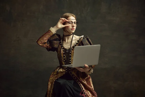年轻女孩 皇室成员 穿着老式服装的公主和现代眼镜在笔记本电脑上工作的画像 背景是深绿色的 历史的概念 复兴艺术的再现 时代的比较 — 图库照片