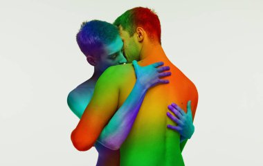 İki erkek, gökkuşağı renginde genç eşcinsel çift beyaz arka planda izole edilmiş bir şekilde sarılıyorlar. Homoseksüel aşk. lgbt topluluğu kavramı, destek, sevgi, insan hakları, hoşgörü ve eşitlik