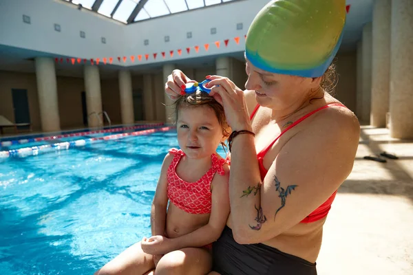 Uśmiechnięta Szczęśliwa Matka Zakładająca Gogle Swoją Piękną Córeczkę Pływanie Basenie — Zdjęcie stockowe