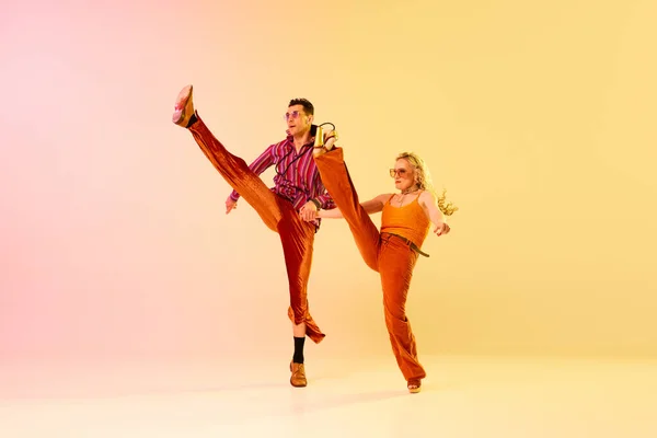 迪斯科舞曲活泼 有表现力的夫妇 穿着老式服装的男女 在渐变的粉色黄色背景下表演 复古风格 业余爱好 音乐的概念 70年代 — 图库照片