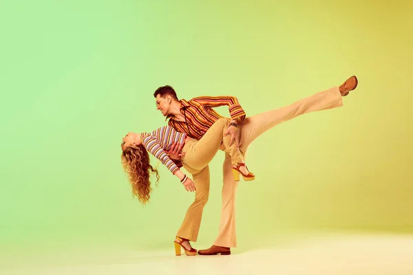 很浪漫的样子年轻漂亮的一对 穿着老式时尚服装的男女 在渐变的绿色背景下跳迪斯科舞 复古风格 业余爱好 音乐的概念 70年代 — 图库照片