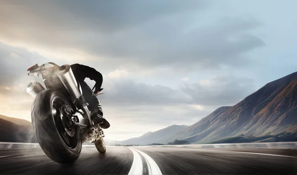 stock image Back bottom view image of man, professional motorbike rider on road, riding with high speed around mountains. 3D render background. Concept of motosport, speed, leisure, hobby, active lifestyle