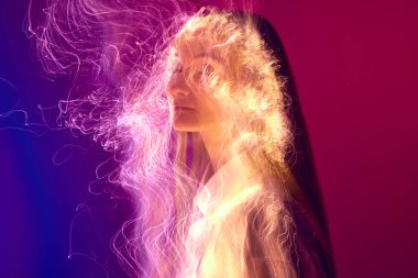 Yanan sanat. Vücudunda neon renkli ışık yansıması olan genç ve narin bir kız, değişken mor arka plana karşı. Sanat anlayışı, modern tarz, siber punk, fütürizm ve yaratıcılık