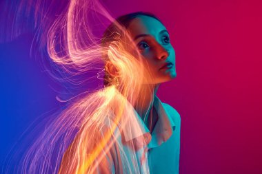 Gradyan mavi pembe stüdyo arka planında neon ışık efektiyle poz veren genç bir kızın portresi. Yaratıcı vizyon. Sanat anlayışı, modern tarz, siber punk, fütürizm ve yaratıcılık