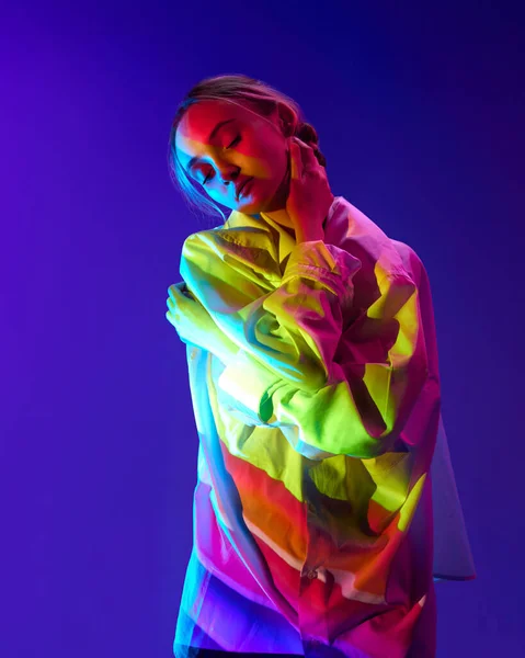 体に多色のネオンフィルターの反射を持つ若い柔らかい女の子の肖像画は 紫色の背景に対してポーズ アート モダンスタイル サイバーパンク 未来主義と創造性 感情の概念 — ストック写真