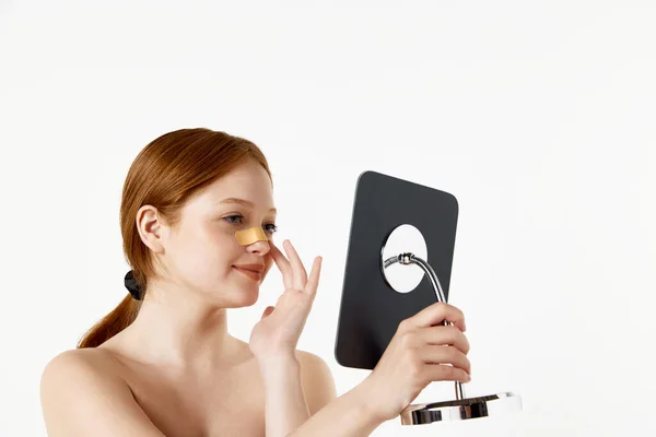 白いスタジオの背景に鏡を見て鼻の上に包帯で幸せ 美しい女の子 美容整形 鼻形成ケア 健康の概念 — ストック写真
