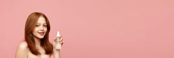 美しく 健康的な よくピンクの背景に顔のトナーを保持肌を持つ赤毛の女の子 自然の美しさ メイク 化粧品 化粧品 スキンケアの概念 バナーだ 広告のコピースペース — ストック写真