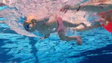 Küçük tatlı bir kız çocuğu, su sporları eğitmeniyle yüzme havuzunda yüzen bir çocuk, antrenman. Spor anlayışı, sağlıklı ve aktif yaşam tarzı, çocukluk, eğlence ve eğitim