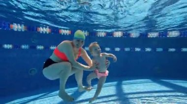 Mutlu anne ve küçük çocuk, kız, kız yüzme, sıcak güneşli bir günde kapalı havuzda oynamak. Yüzmeyi öğreniyorum. Spor anlayışı, sağlıklı ve aktif yaşam tarzı, çocukluk, eğlence ve eğitim