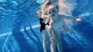 Küçük bebekler, yüzme havuzunda anneleriyle yüzen kızlar, suya dalmak, eğlenmek. Spor anlayışı, sağlıklı ve aktif yaşam tarzı, çocukluk, eğlence
