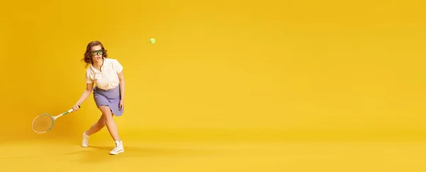 专注的女孩穿着运动服 打网球打球拍黄色工作室背景 运动的概念 积极的生活方式 班纳广告的复制空间 — 图库照片