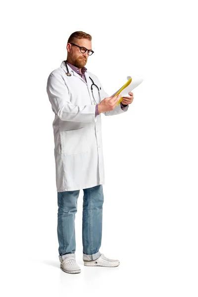 大胡子严肃男子的画像 身穿白衣的医生 带着听诊器 对照白底阅读医疗文件 医疗保健 专业的概念 — 图库照片