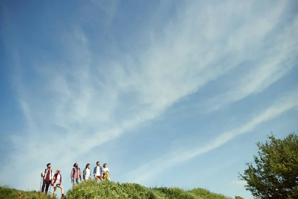 青空と緑のピーク 若者のグループは 友達とハイキングに行く 丘の上に立って美しい風景を楽しむ アクティブなライフスタイル スポーツ 友情の概念 — ストック写真