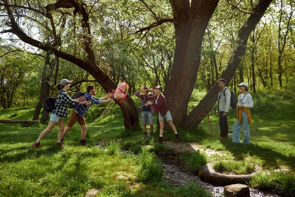 在户外享受周末 年轻人 男人和女人 朋友去远足 在森林里散步 在温暖的日子里跳过河 积极生活方式 运动和业余爱好 友谊的概念 — 图库照片