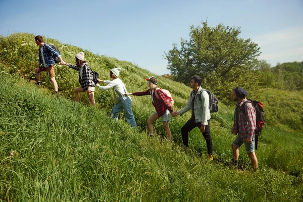 一群年轻人 朋友们在温暖的春日漫步上山 男人和女人去远足 欣赏风景 积极生活方式 运动和业余爱好 友谊的概念 — 图库照片