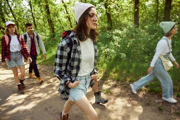 若者のグループは スタイリッシュな快適な服の友人は 暖かい晴れた日にハイキングに行く森の道を歩く アクティブなライフスタイル スポーツ 友情の概念 — ストック写真