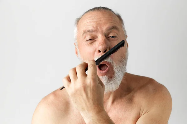 수염을 기르고 턱수염을 기르고 턱수염을 솔질하는 잘생긴 남자의 모습은 배경에 — 스톡 사진