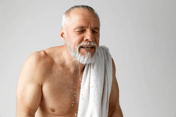 大人の肖像画 白髪の男は灰色の背景に皮膚の後の世話をし 朝のルーチンを行う 顔を洗う 男性の美しさ 顔と肌のケア 毎日の手順 年齢の概念 — ストック写真