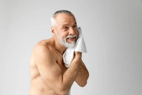 ハンサムな 成熟した 白髪の男の肖像画は 灰色の背景に顔を洗う朝のルーチンを行う 男性の美しさ 顔と肌のケア 毎日の手順 年齢の概念 — ストック写真
