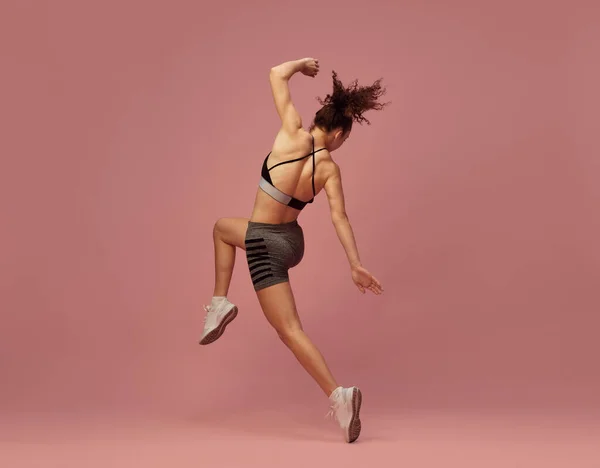 フルボディワークアウト スポーツウェアのトレーニングで若いスポーツ女性のダイナミックなイメージ ピンクのスタジオの背景に対して動きにポーズ スポーツライフスタイル 美しさ ボディケア フィットネス 健康の概念 — ストック写真