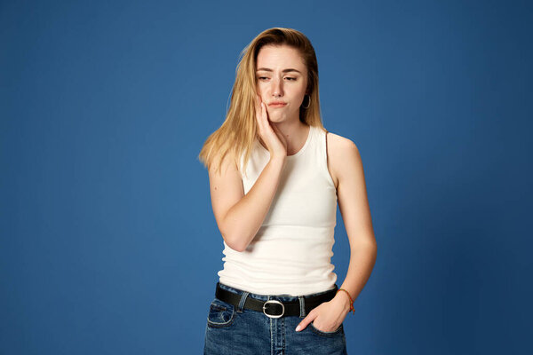 Портрет молодой девушки, стоящей с задумчивым лицом на синем фоне студии. Мозговой штурм. Концепция молодости, человеческих эмоций, выражения лица, образа жизни, бизнеса