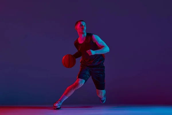 Młody Zmotywowany Sportowiec Koszykarz Ruchu Podczas Gry Trening Fioletowym Tle — Zdjęcie stockowe