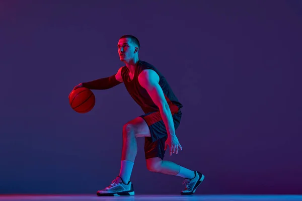 Młody Mięśniak Koszykarz Ruchu Dryblująca Piłka Fioletowym Tle Studia Neonowym — Zdjęcie stockowe