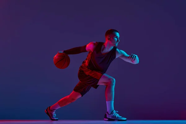 Junger Athletischer Mann Basketballspieler Bewegung Mit Ball Vor Lila Studiohintergrund — Stockfoto