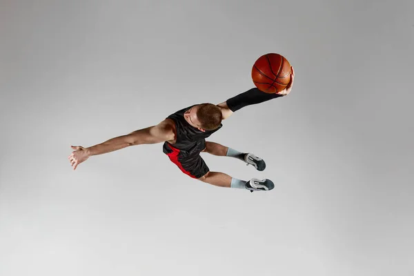 获胜的进球 活泼的年轻人 运动中的篮球运动员 带着球在灰色的工作室背景下跳跃 顶部视图 职业运动 业余爱好 健康生活方式 动作和运动的概念 — 图库照片