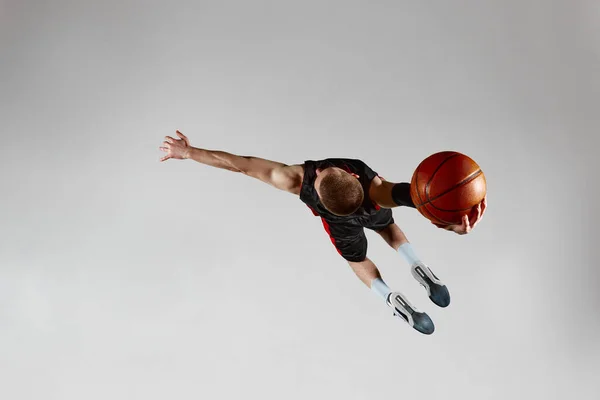 有动力的运动员 运动的男性篮球运动员 带着球在灰色工作室的背景下跳跃 顶部视图 灌篮灌篮 职业体育 健康生活方式 行动和运动的概念 — 图库照片