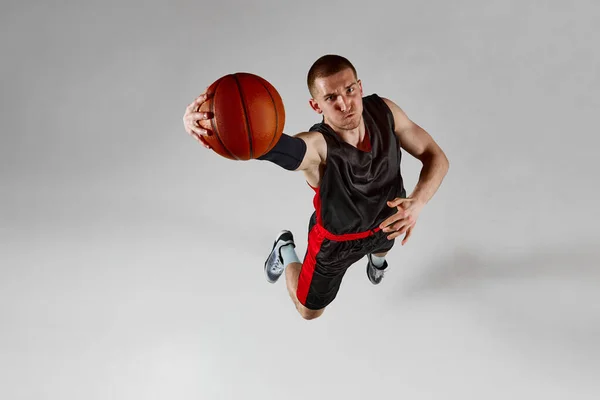 Geconcentreerde Sporter Mannelijke Basketballer Beweging Springen Met Bal Tegen Grijze — Stockfoto