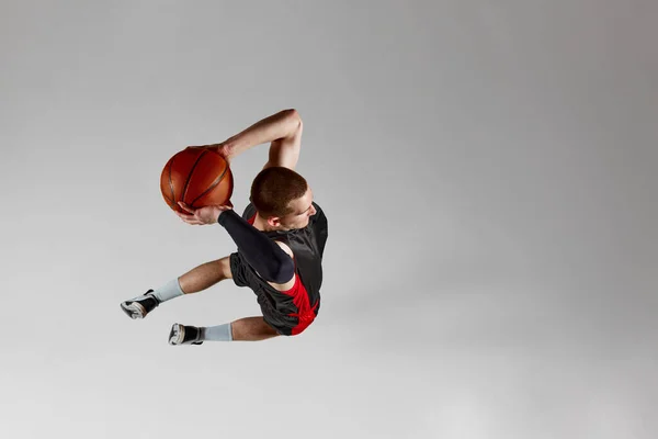 有动力的 专注的年轻人 篮球运动员抛出所有在一个灰色工作室背景的跳跃 空中风景 灌篮灌篮 职业体育 行动和运动的概念 — 图库照片