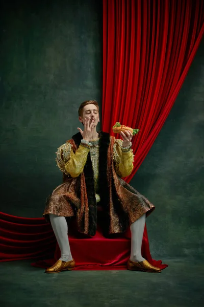ヴィンテージの背景に熱い犬を食べるヴィンテージの服の若い男 王族として男性モデル ルネサンス美術 リメイクの比較の概念 — ストック写真