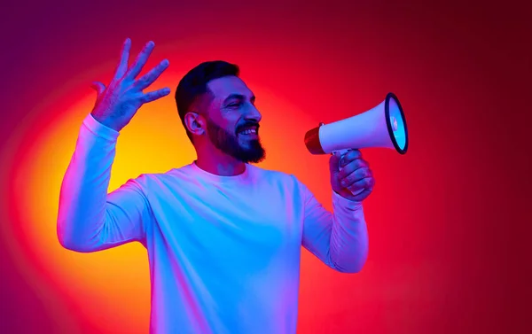 在霓虹灯下 穿着条纹衬衫的兴奋 微笑的男人用扩音器对着渐变红的工作室背景大喊 人类情感 面部表情 生活方式的概念 — 图库照片
