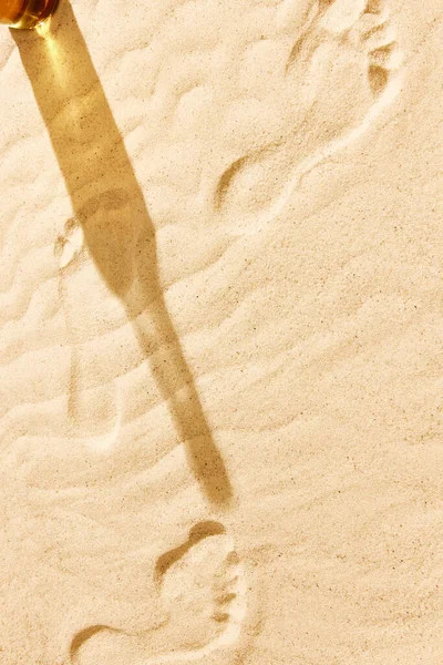 啤酒瓶在温暖的沙滩上的阴影 纹理图像 沙上有脚印 在温暖的夏日里 海滩上的寒意 伴随着清凉的饮料和清凉的饮料 酒的概念 酿酒厂 — 图库照片