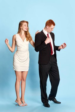 Resmi takım elbiseli yakışıklı genç adamın portresi mavi stüdyo geçmişiyle güzel kız arkadaşına evlenme teklif etmeye hazırlanıyor. Aile kavramı, ilişki, gençlik, duygular, eğlence. Ad