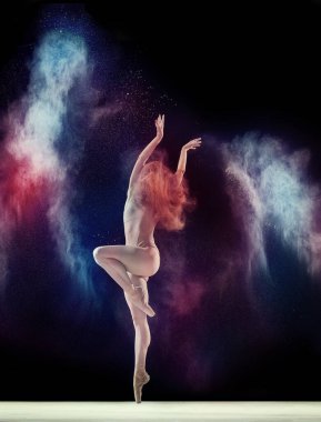 Genç bir kız, profesyonel balerin bej elbiseli, siyah stüdyo arka planında renkli tozla dans ediyor. Şefkat. Sanat kavramı, festival, dans güzelliği, ilham, gençlik