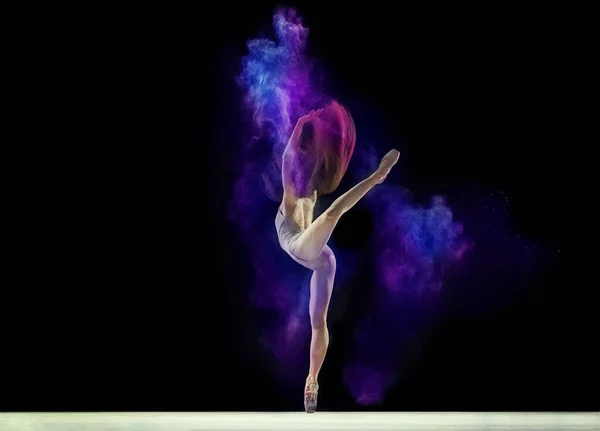 年轻的女孩 穿着米色紧身衣的柔韧的芭蕾舞演员站在尖上 在黑色工作室的背景下 与五彩缤纷的粉末跳舞 艺术概念 舞蹈之美 — 图库照片