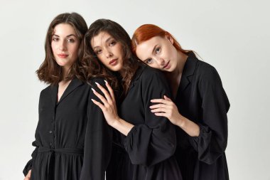 Destek ve dostluk. Siyah elbiseli genç, narin ve güzel kadınların portresi. Işık stüdyosu arka planında. Zarif moda kavramı, kadın güzelliği, iş, alışveriş, satış, reklam