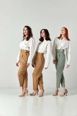 Zarif giysiler, bluz ve pantolonlar içinde stüdyo arka planında poz veren güzel genç kadınların tam boy portresi. Zarif moda kavramı, kadın güzelliği, iş, alışveriş, satış, reklam
