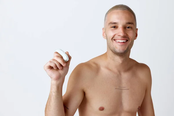 白いスタジオの背景に消臭剤を使用して よく手入れされた肌を持つハンサムな若い男の肖像画 軽薄なポーズ 男性の美しさ スキンケア 健康の概念 広告のコピースペース — ストック写真
