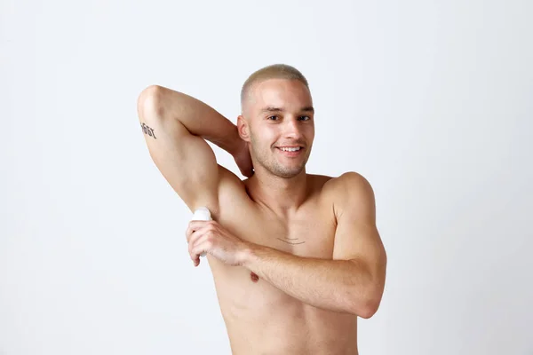 白いスタジオの背景に消臭剤を使用して よく手入れされた肌を持つハンサムな若い男の肖像画 軽薄なポーズ 男性の美しさ スキンケア 健康の概念 広告のコピースペース — ストック写真