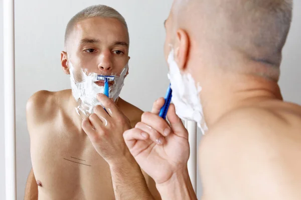 Retrato Joven Sin Camisa Afeitándose Barba Mirándose Espejo Sobre Fondo — Foto de Stock