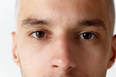 Beyaz stüdyo arka planında kameraya bakan kahverengi gözlü adamın yakın plan görüntüsü. Erkeklerin güzellik anlayışı, cilt bakımı, kozmetoloji, spa, sağlık. İlan için alanı kopyala