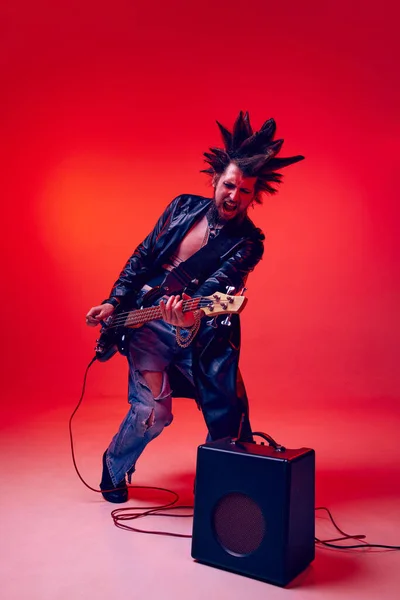 年轻的男人 庞克在霓虹灯下的红色工作室背景下弹奏电吉他 生活方式 亚文化 人类情感的概念 — 图库照片