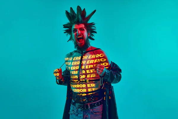 若い男 ロックミュージシャン 体にネオンフィルター反射とパンク ネオンの光の中で青のスタジオの背景に対してポーズ ライフスタイル サブカルチャー アート 人間の感情の概念 — ストック写真