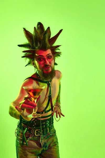 年轻的赤身裸体男子 双关语在非凡的发型喝鸡尾酒 在霓虹灯下的绿色工作室背景下摆姿势 生活方式 亚文化 人类情感的概念 — 图库照片
