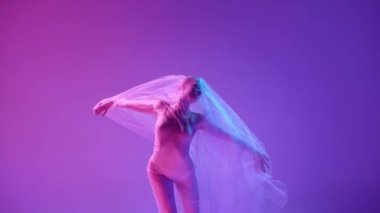 Genç, güzel, şeffaf duvağıyla neon ışıkta pembe stüdyo arka planında dans eden şeffaf bir balerin. Klasik sanat, dans, güzellik, ilham, yaratıcılık kavramı